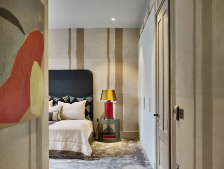 Modern bedroom interior with striped wallpaper and abstract art.