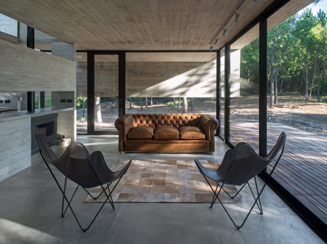 Spacious indoor-outdoor living space with concrete walls, wooden ceiling, and leather sofa.