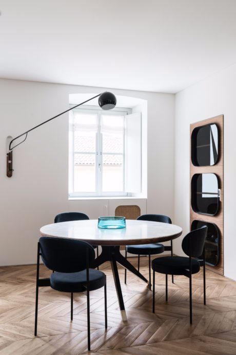 Modern dining room with a round wooden table, black chairs, and a unique lighting fixture.