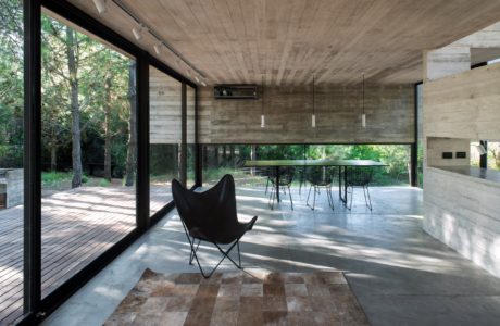 Concrete, wood, and glass create a modern, nature-inspired interior space with a dining area.