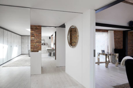 Open-concept room with white walls, brick accents, and minimalist furniture.