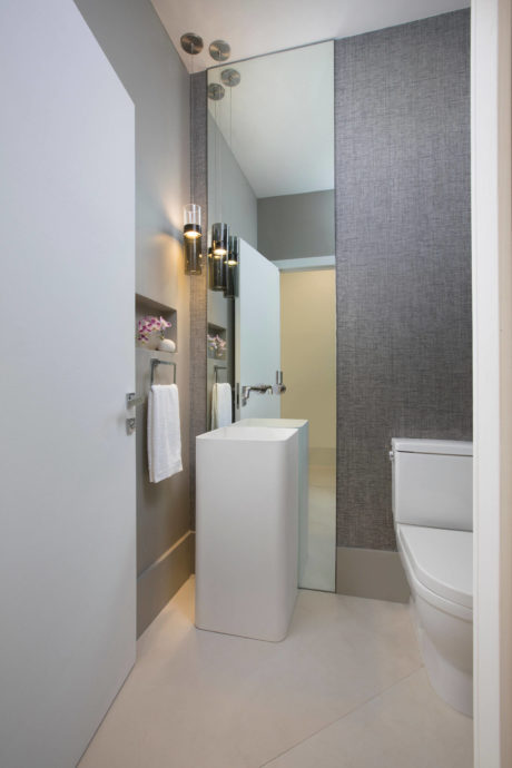 Modern bathroom with sleek vanity, backlit mirror, and textured gray wall panels.