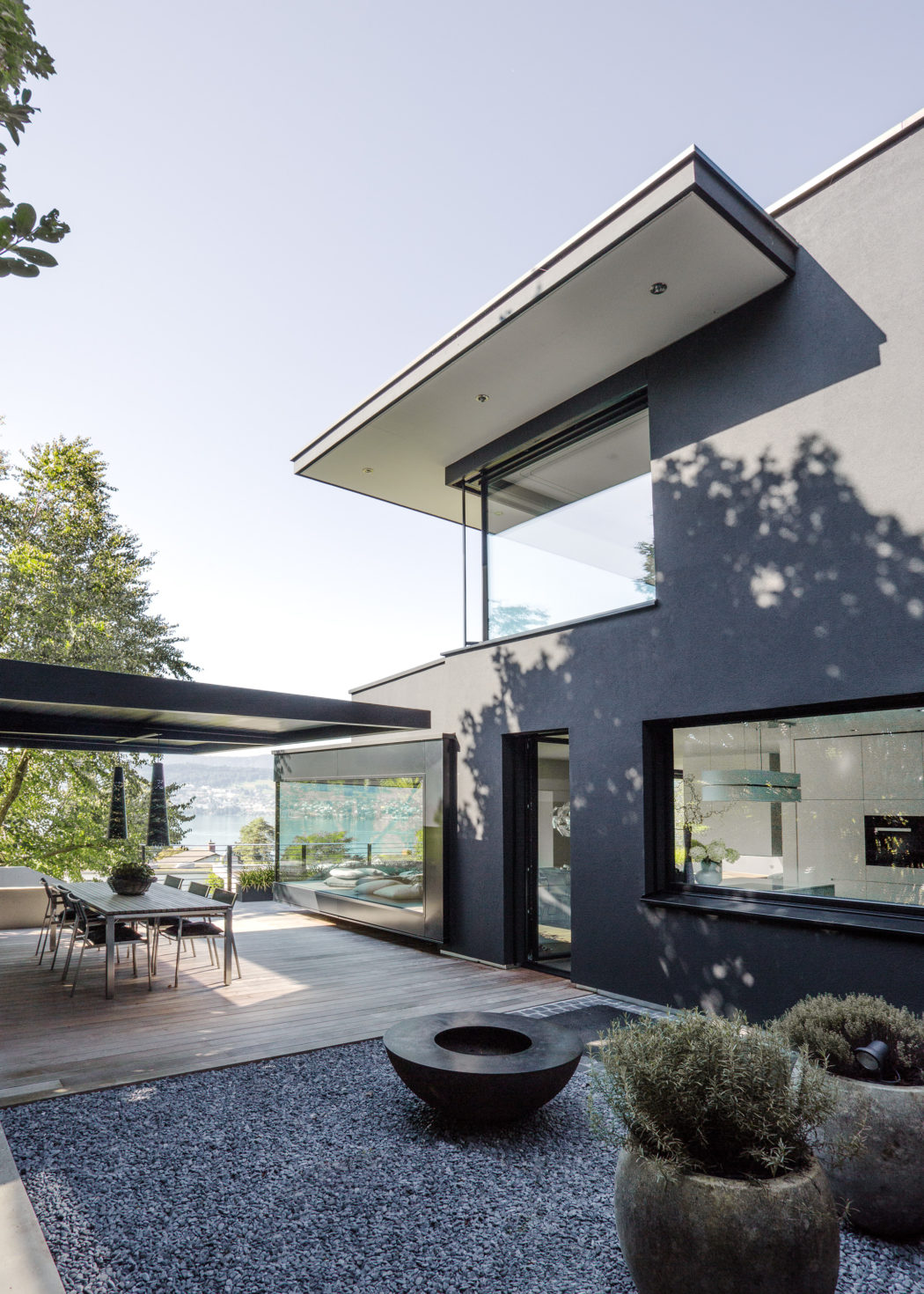 Sleek, modern architectural design with expansive glass walls, angled roofs, and a cozy outdoor patio.