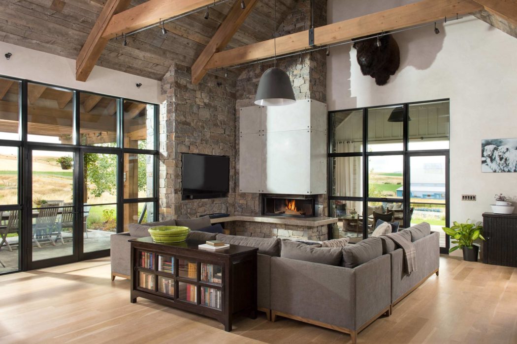 Spacious living room with fireplace, wooden beams, and large windows.