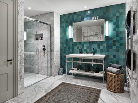 Modern bathroom with marble tiles and teal accent wall.