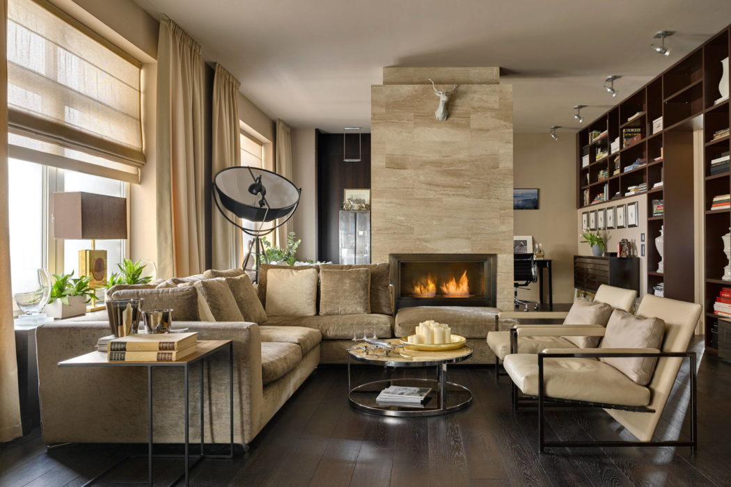 A cozy living room with a fireplace, sectional sofa, and built-in shelving showcasing decor.