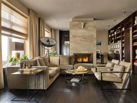 A cozy living room with a fireplace, sectional sofa, and built-in shelving showcasing decor.