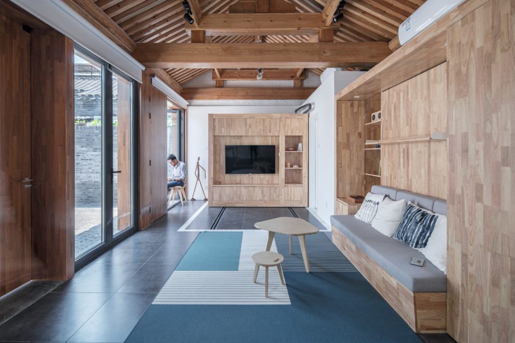Spacious living room with wood-paneled walls, exposed beams, and sleek furnishings.