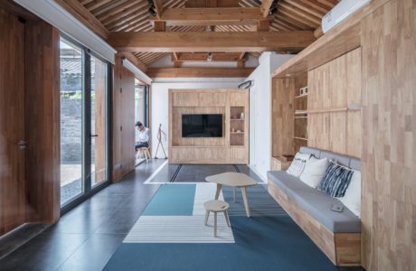 Spacious living room with wood-paneled walls, exposed beams, and sleek furnishings.