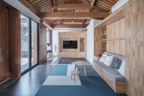 Spacious living room with wood-paneled walls, exposed beams, and sleek furnishings.