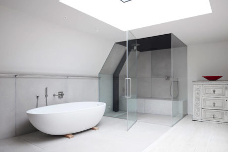 A modern, minimalist bathroom with a freestanding tub, glass shower enclosure, and built-in cabinetry.