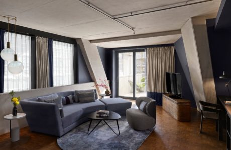 Contemporary living room with exposed concrete beams, plush seating, and herringbone