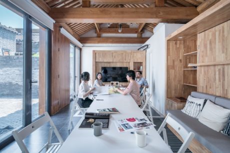 A cozy, open-concept living space with wooden beams, shelving, and comfortable seating.