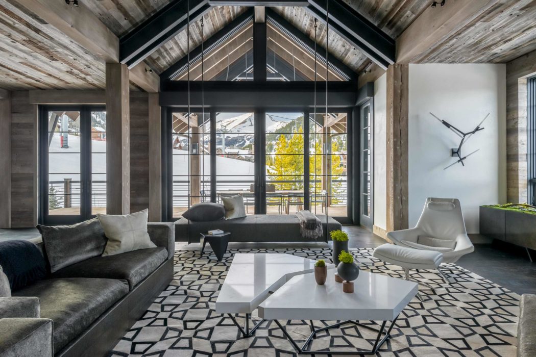 Contemporary living room with exposed beams, geometric rug, and mountain view.