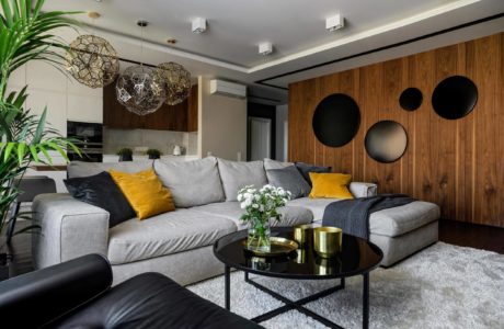 Sleek modern living room with gray couch, black coffee table, and natural wood wall accents.