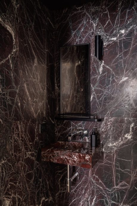 Sleek, modern bathroom vanity with minimalist black frame against dark marble wall.