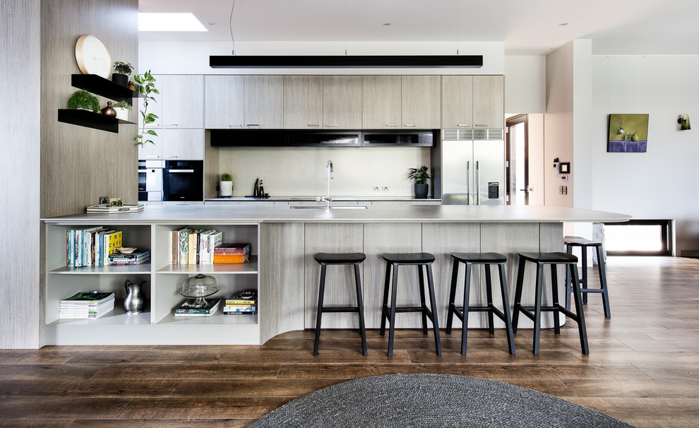 Modern, open-concept kitchen with sleek gray cabinetry, floating shelves, and bar seating.
