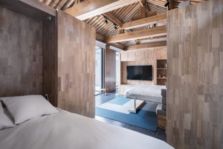 A cozy, rustic bedroom with wood-paneled walls, a vaulted ceiling, and built-in shelving.