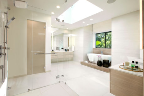 Spacious, light-filled bathroom features glass shower, vanity, and access to garden.