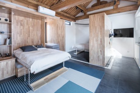Cozy, rustic-style bedroom with wooden walls, slanted ceiling, and modern furnishings.