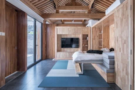 A spacious and warmly-lit bedroom with a wooden ceiling, modern furniture, and large windows.