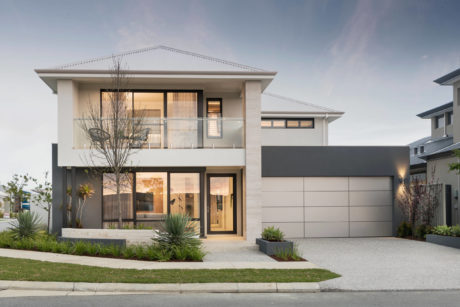 Modern two-story house with balcony and attached garage at dusk.
