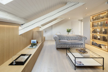 Modern living room with chesterfield sofa, wood paneling, and shelving