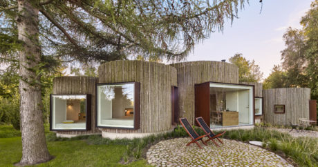 Modern house with wooden slats exterior and large windows in a garden setting.