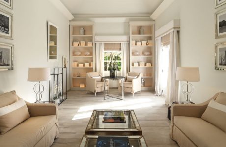 Elegant living room with beige sofas, a glass table, built-in booksh