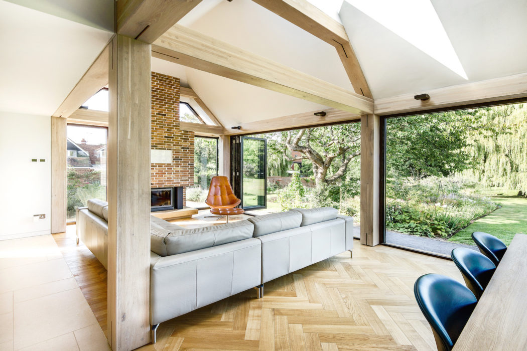 Contemporary room with exposed beams, herringbone floor, and large windows overlooking