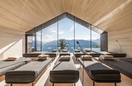 Modern room with large windows, wooden walls, and multiple daybeds overlooking a