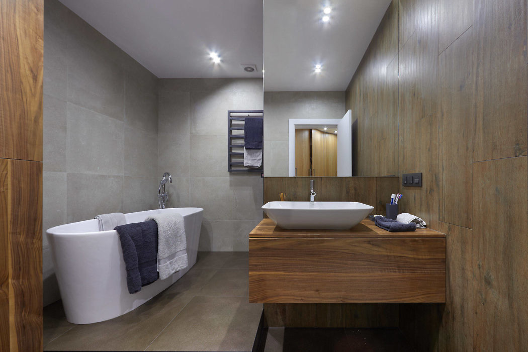 Modern bathroom with freestanding tub, wooden vanity, and gray tiles.