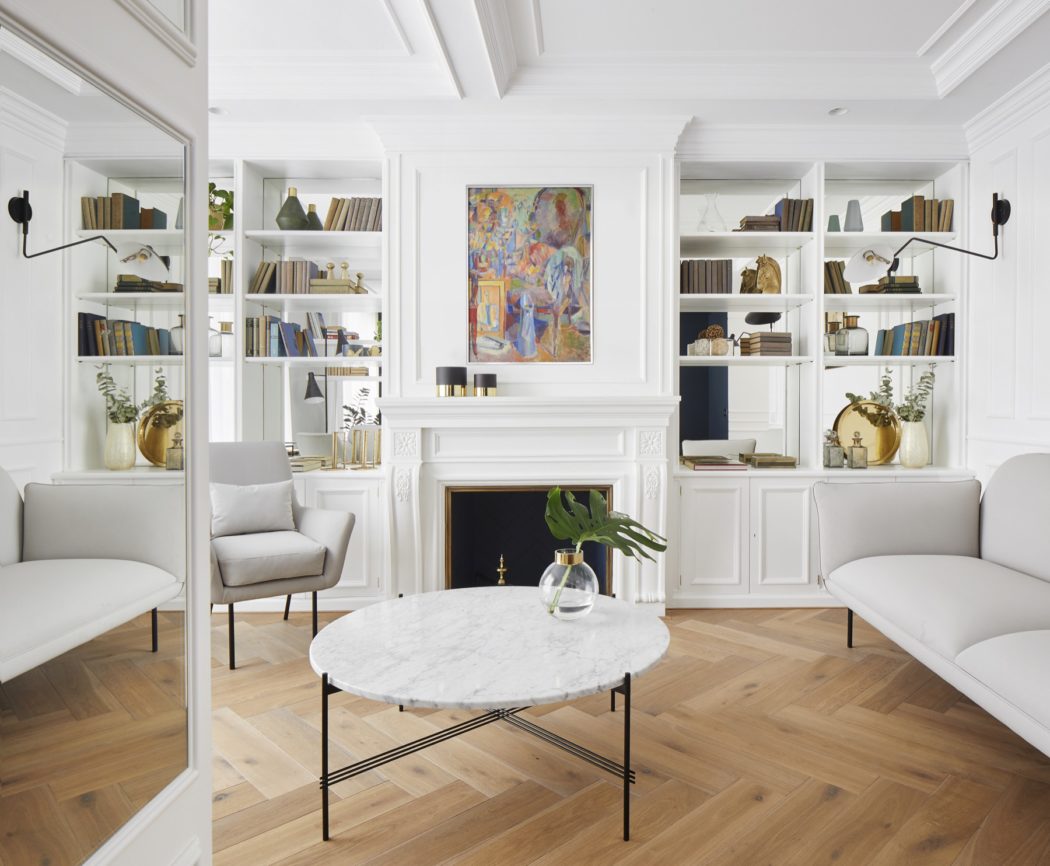 Elegant living room with white built-in bookshelves, a marble table,