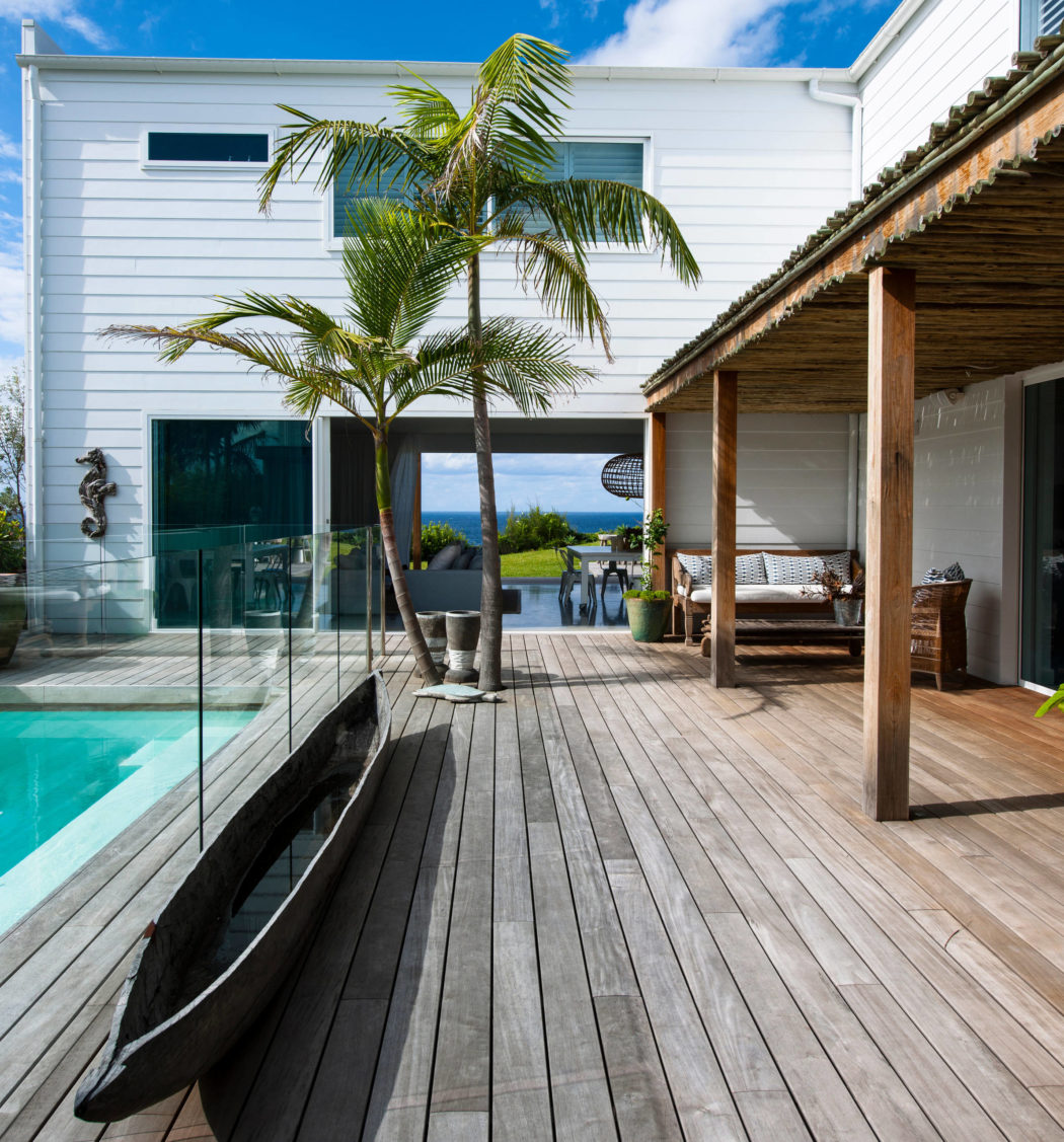 Contemporary house with pool, wooden deck, and palm tree.