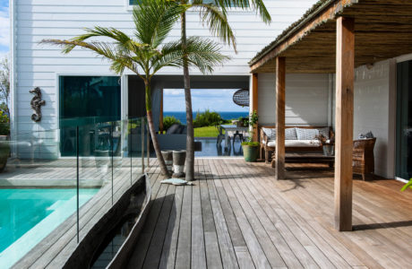 Contemporary house with pool, wooden deck, and palm tree.