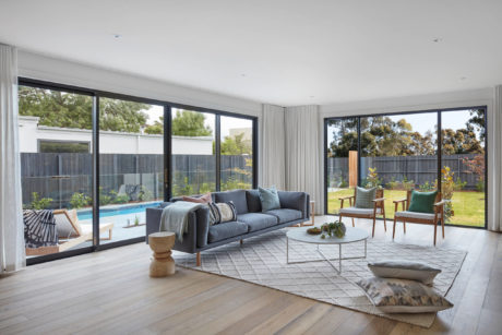 Modern living room with large windows overlooking a pool.