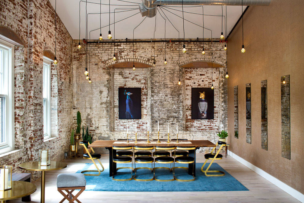 Modern dining room with exposed brick walls, long table, blue chairs, and unique