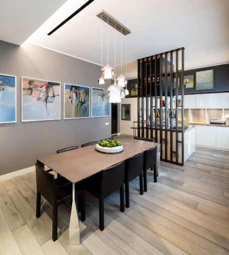 Modern dining room with pendant lights, artwork, and a partition leading to the kitchen