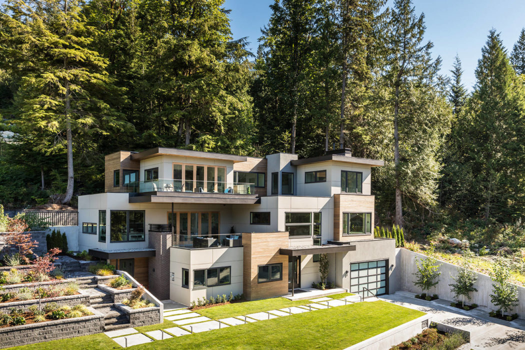 Contemporary multi-level home with large windows nestled in a forest.