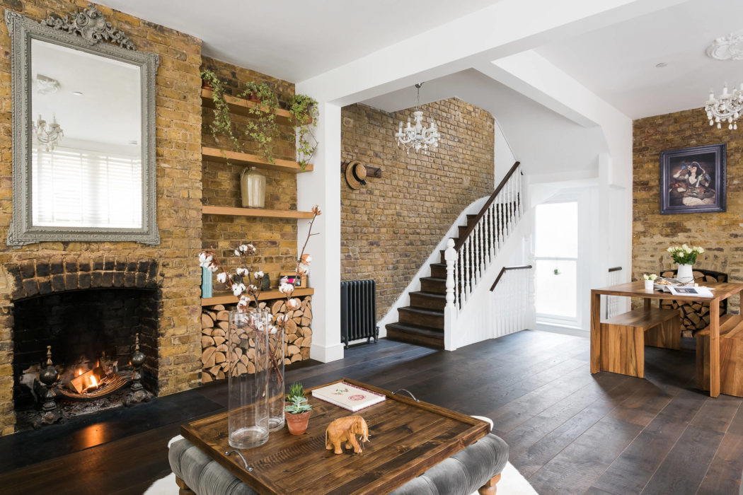 Elegant room with exposed brick, fireplace, and white staircase.