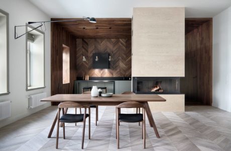 Modern kitchen with wooden accents and dining table set near a fireplace.