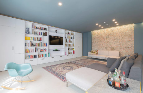 Modern living room with built-in bookshelf, brick wall accent, and contemporary furniture