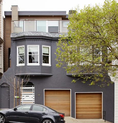 Contemporary townhouse with dark facade and wooden garage doors.