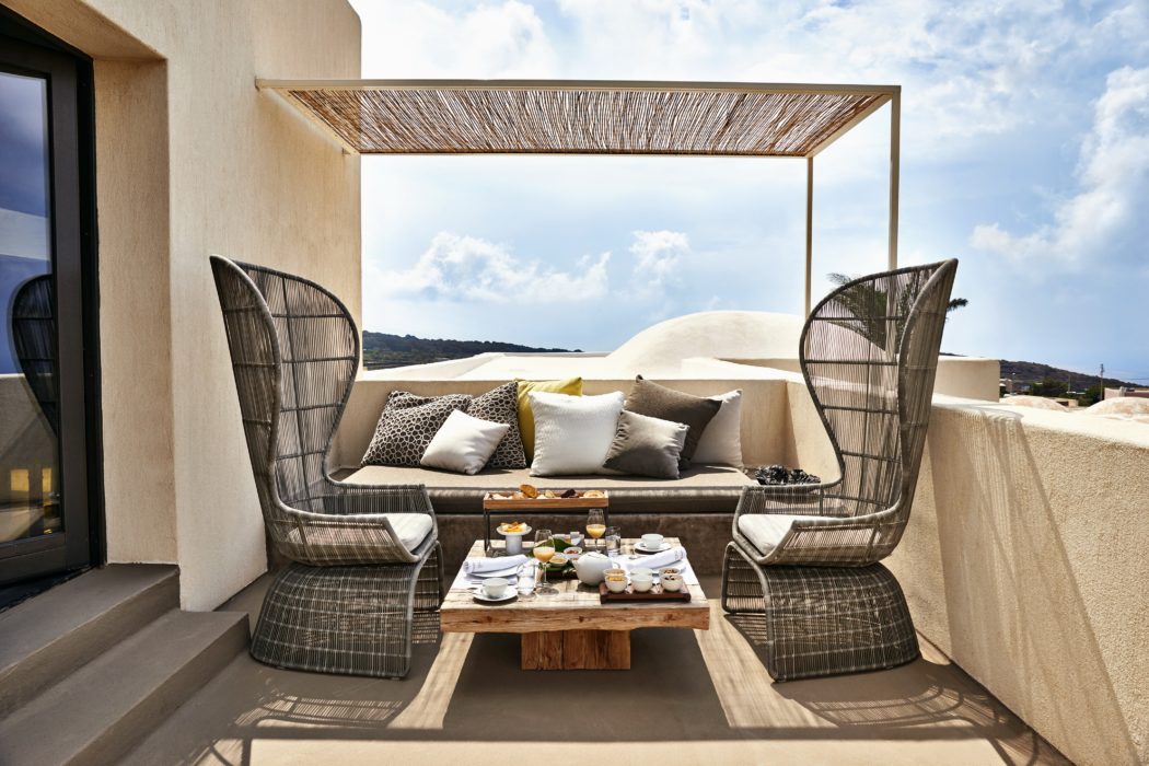 Outdoor terrace seating area with a canopy, sofa, chairs, and a table with