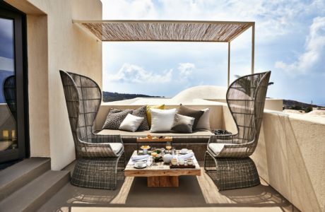 Outdoor terrace seating area with a canopy, sofa, chairs, and a table with