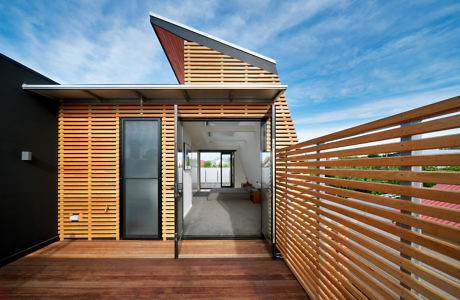 Modern house exterior with open door and wooden deck.