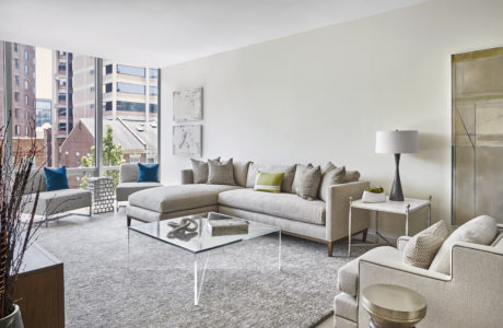 Contemporary living room with neutral tones and glass coffee table.