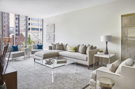 Contemporary living room with neutral tones and glass coffee table.