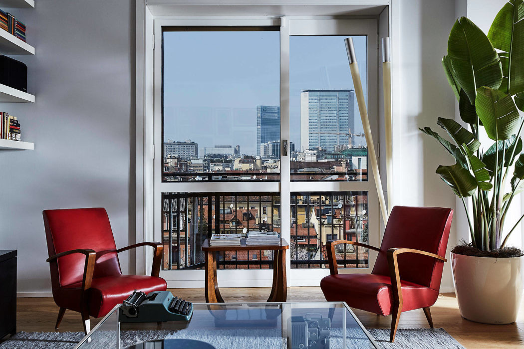 Contemporary room with red chairs, glass table, and city view.