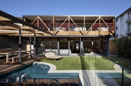 Modern backyard with pool, wooden deck, and house with large windows.